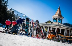 JoSchi-Bar, © JoSchi-Bar Skifahrer vor der JoSchi-Bar mit Skiern und Snowboards im Schnee.