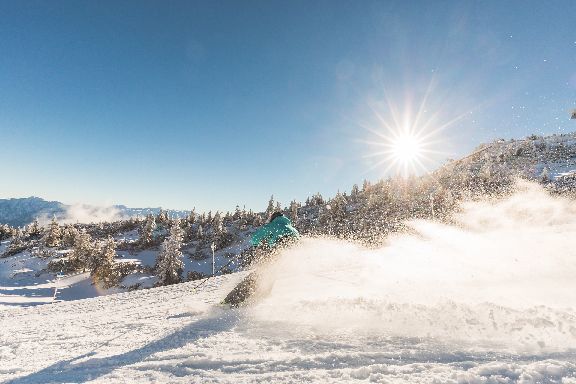 Die strahlende Morgensonne taucht die schneebedeckten Hänge in ein magisches Licht, während Skifahrer durch den frischen Pulverschnee gleiten. Die klare Luft und die majestätischen Berge schaffen eine unvergleichliche Atmosphäre für ein unvergessliches Skierlebnis.
