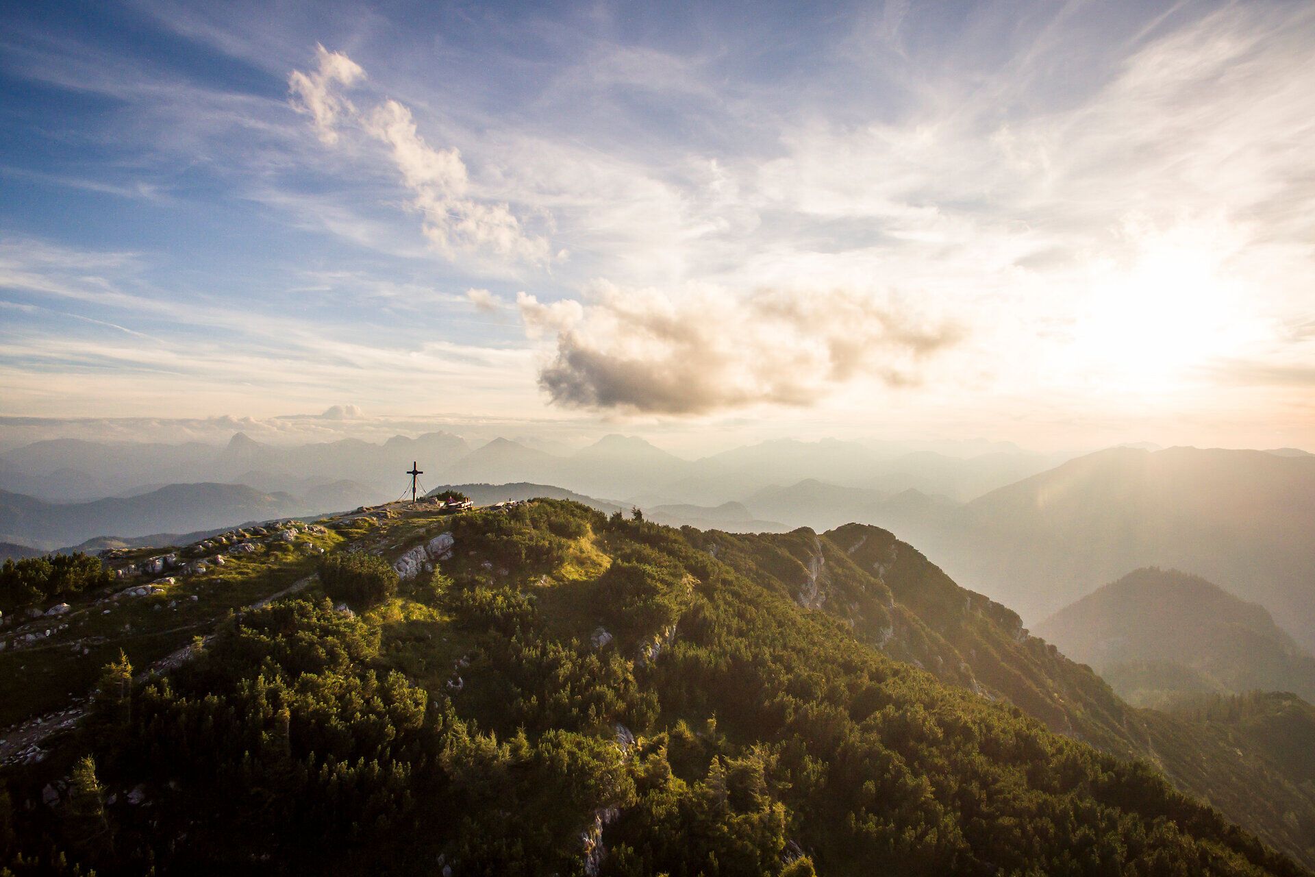 Der Sonnenuntergang taucht die majestätischen Berge in ein warmes, goldenes Licht und schafft eine atemberaubende Kulisse. Die sanften Hügel und die dichten Wälder laden zu unvergesslichen Erlebnissen in der Natur ein. Hier, wo der Himmel die Erde küsst, spürt man die Ruhe und Schönheit der alpinen Landschaft.
