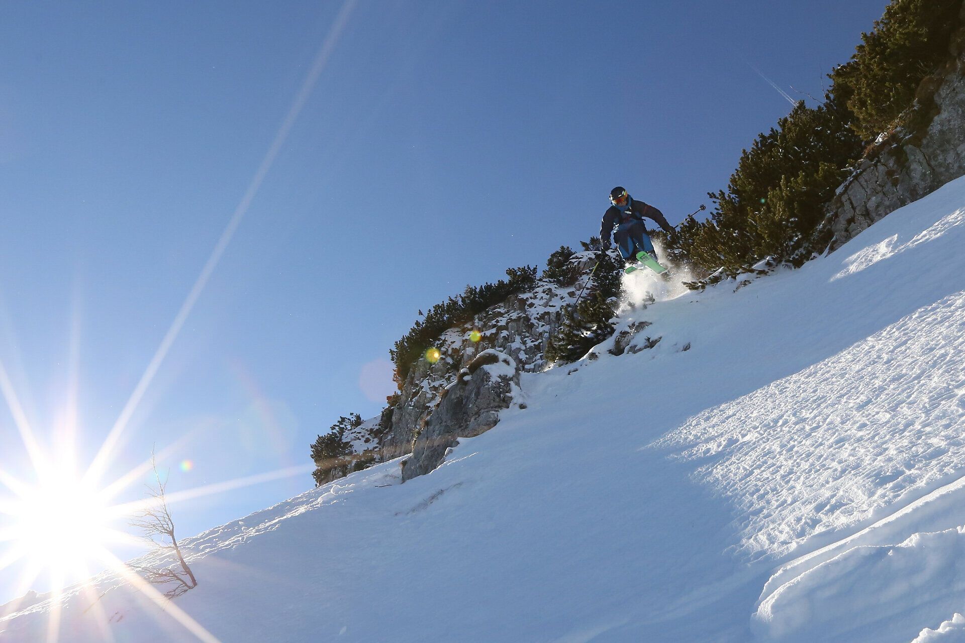 Ein Freerider gleitet elegant durch den frischen Pulverschnee, während die strahlende Sonne über den schneebedeckten Gipfeln aufgeht. Die klare, kalte Luft und die majestätische Berglandschaft schaffen eine unvergleichliche Atmosphäre für Wintersportler. Hier, im Großen Kar, wird jeder Schwung zu einem unvergesslichen Erlebnis.