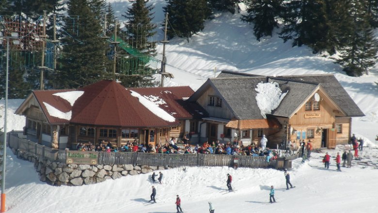 Ski hut Latschen-Alm with skiers in the snow.