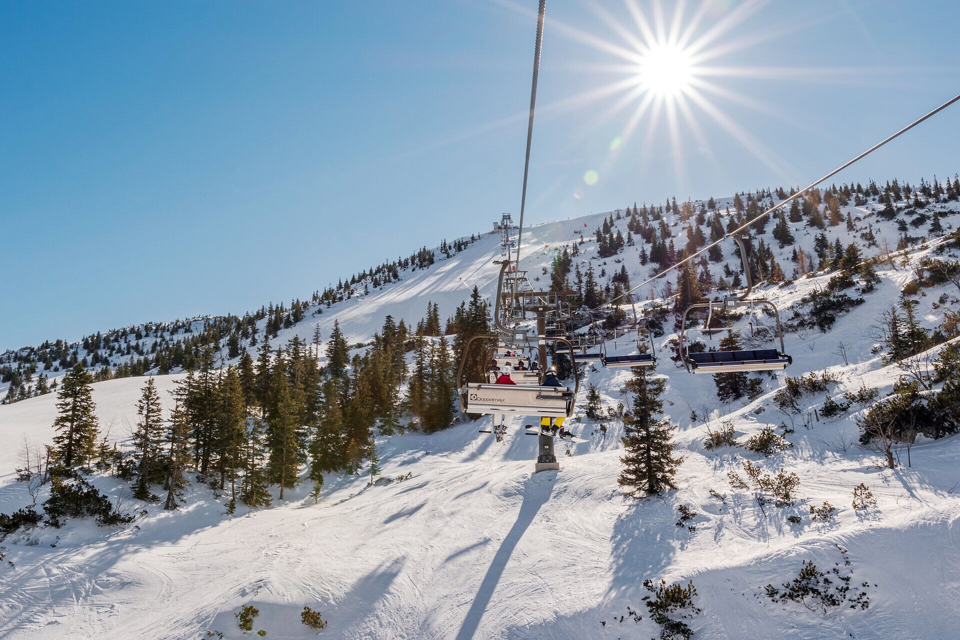 Die strahlende Wintersonne funkelt über die schneebedeckten Hänge, während der Sessellift sanft die Skifahrer in die Höhe befördert. Umgeben von majestätischen Tannen und der frischen Bergluft, lädt dieser Ort zu unvergesslichen Abenteuern im Schnee ein.
