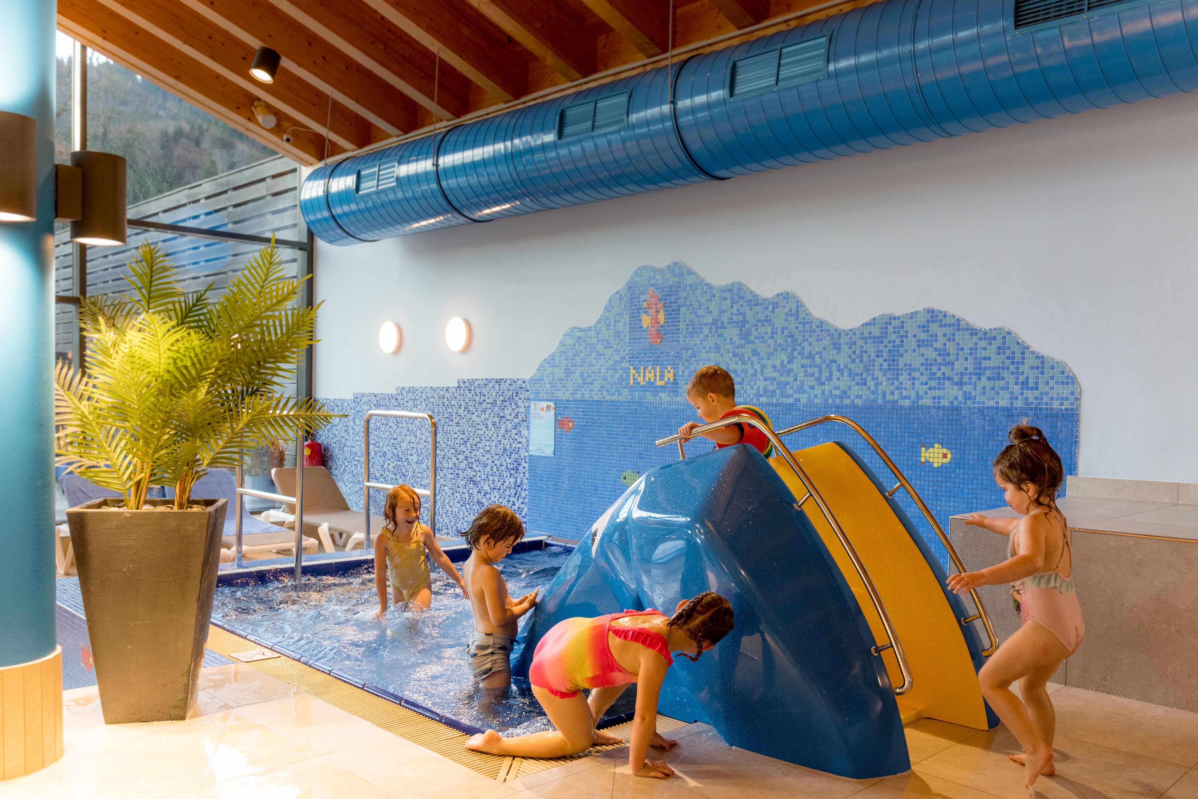 Children are playing in an indoor pool with a small slide at the Ybbstaler Solebad.