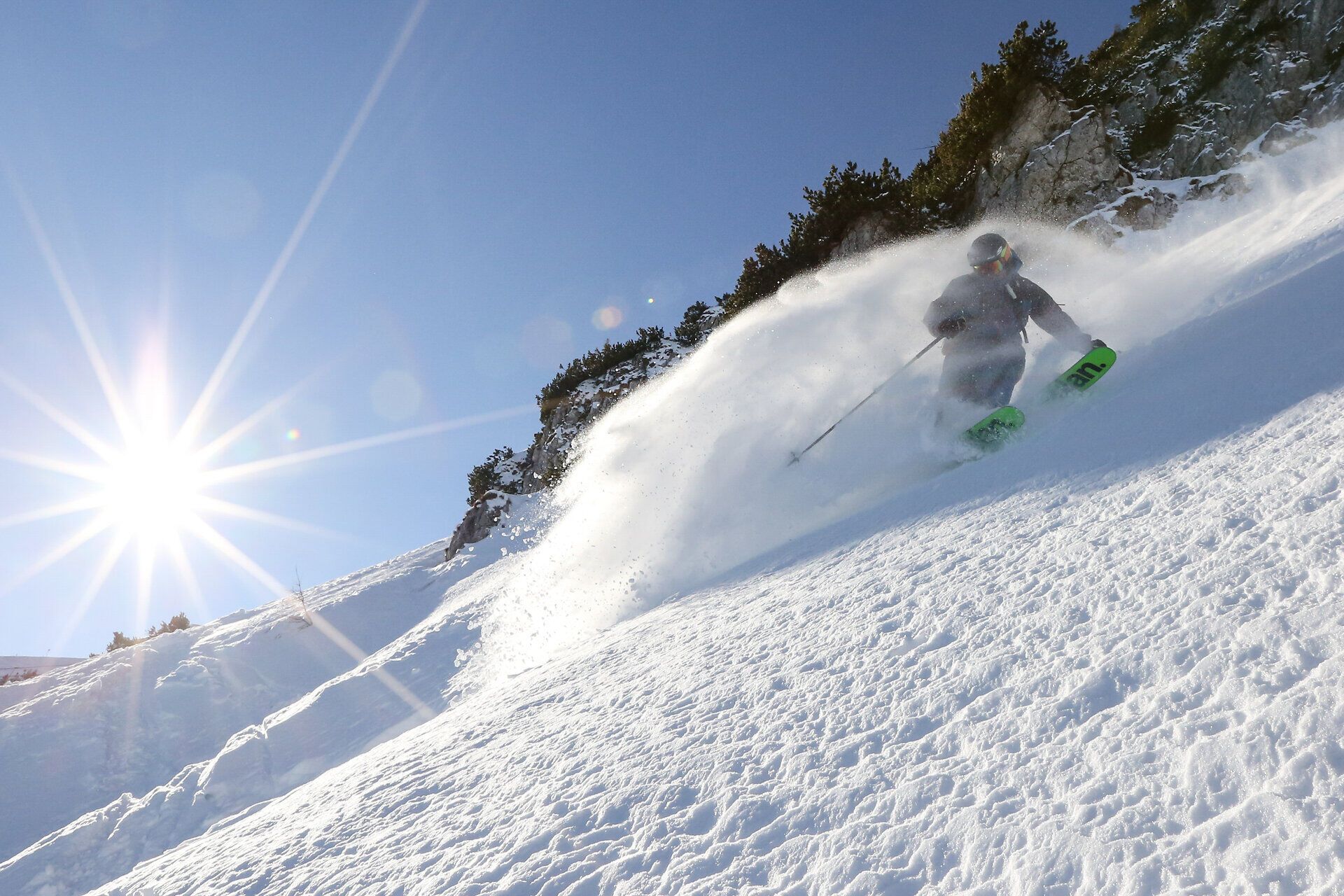 Ein Skifahrer gleitet elegant durch den frischen Pulverschnee, während die strahlende Sonne über den schneebedeckten Gipfeln leuchtet. Die unberührte Landschaft und die klare Luft schaffen eine unvergleichliche Atmosphäre für Freeride-Enthusiasten. Hier, im Großen Kar, wird jeder Schwung zu einem unvergesslichen Erlebnis.